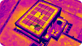 Wärmebildaufnahme einer Photovoltaikanlage auf einem Flachdach mit farbiger Temperaturdarstellung.