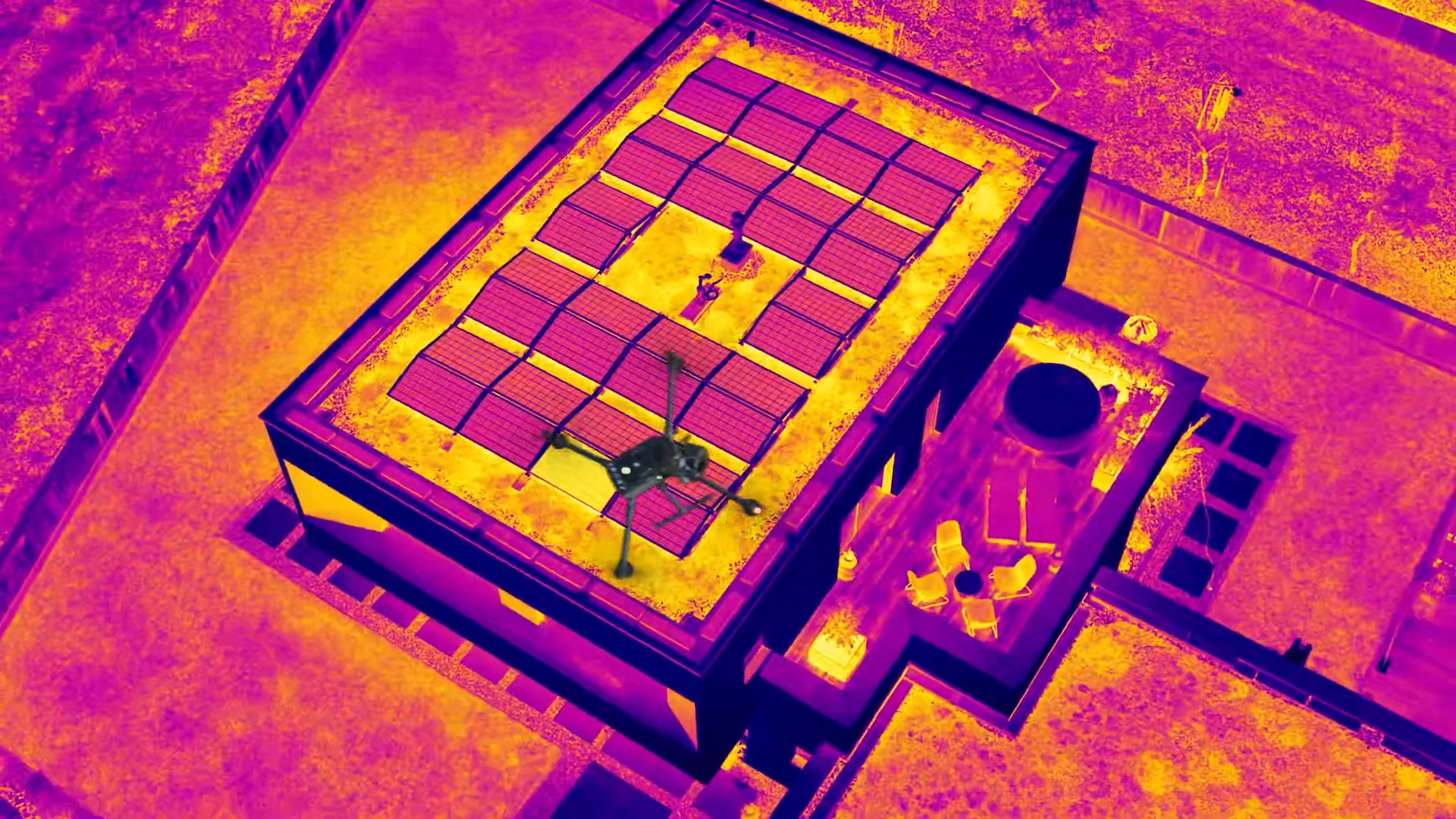 Thermografie-Drohnenaufnahme eines Flachdachs mit Photovoltaik-Modulen in Falschfarben zur Erkennung von Hotspots und Fehlerstellen.