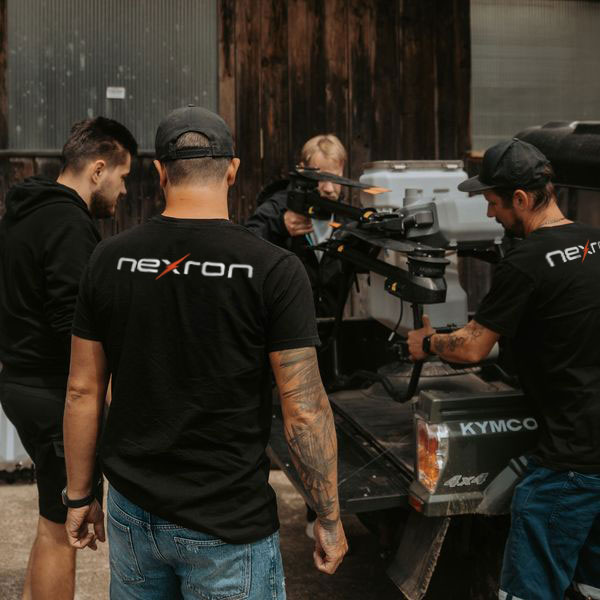 Das Nexron-Team in schwarzen Firmen-T-Shirts bereitet gemeinsam eine große Industriedrohne auf der Ladefläche eines Allradfahrzeugs für die Inspektion einer Photovoltaik-Großanlage vor.